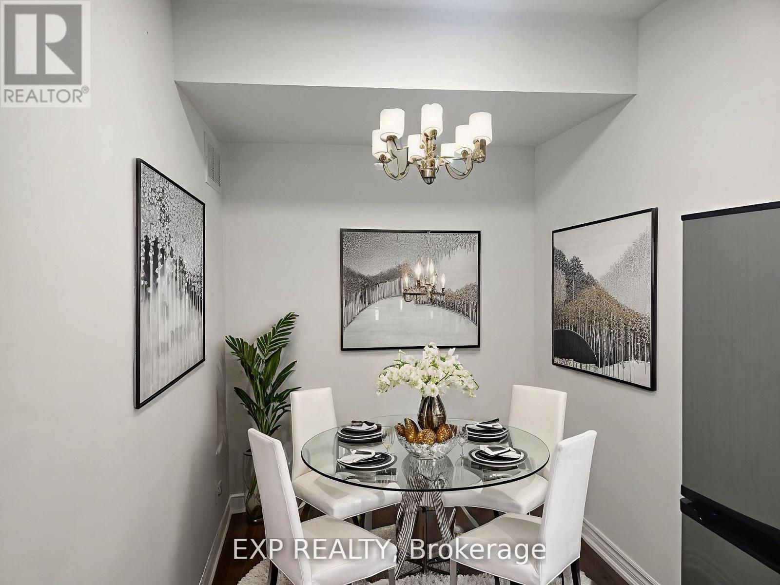 A dining room with a glass table and chairs, a chandelier, and framed pictures on the wall.