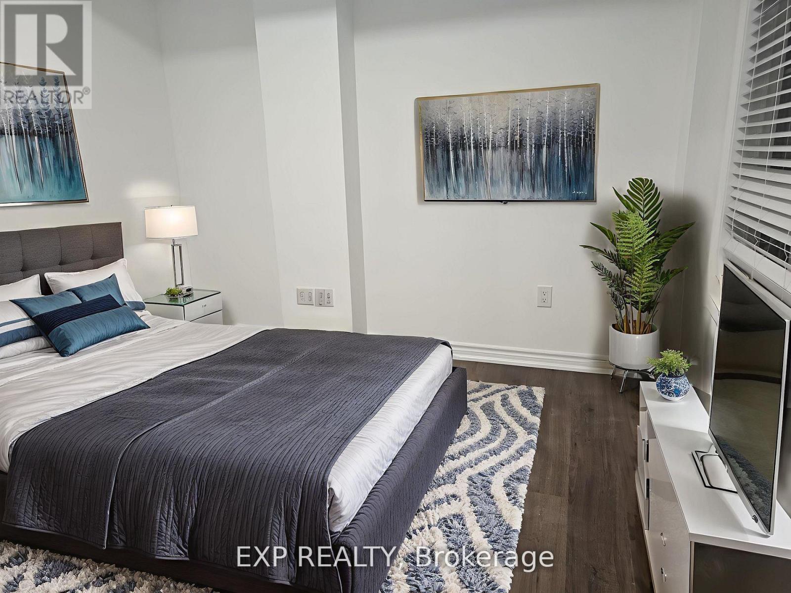 A bedroom with a large bed and a painting on the wall.