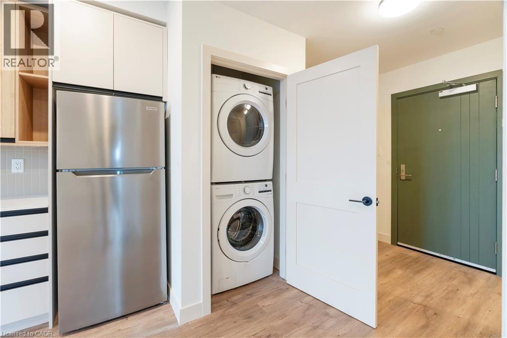 A modern kitchen with a stainless steel refrigerator and a washing machine in the laundry room.