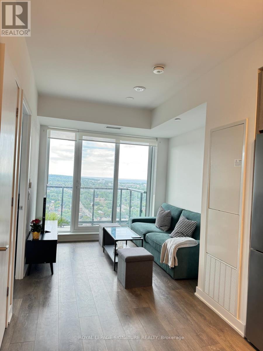 A living room with a couch, a coffee table, and a large window overlooking the city.