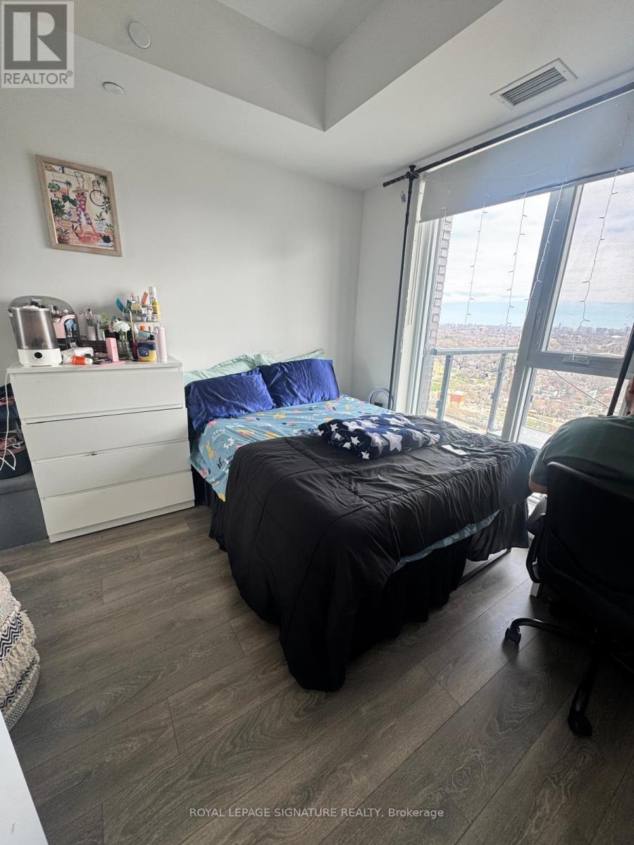 A bedroom with a bed, dresser, and window overlooking a cityscape.