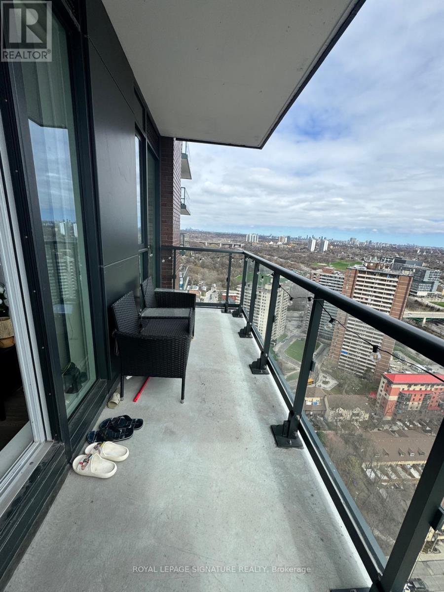 A balcony with a table and chairs overlooking a cityscape.