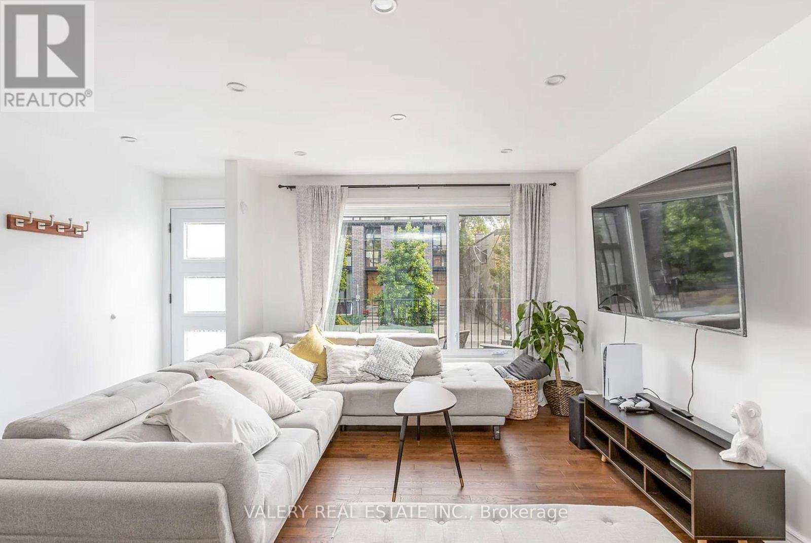 A living room with a grey couch and a television on the wall.