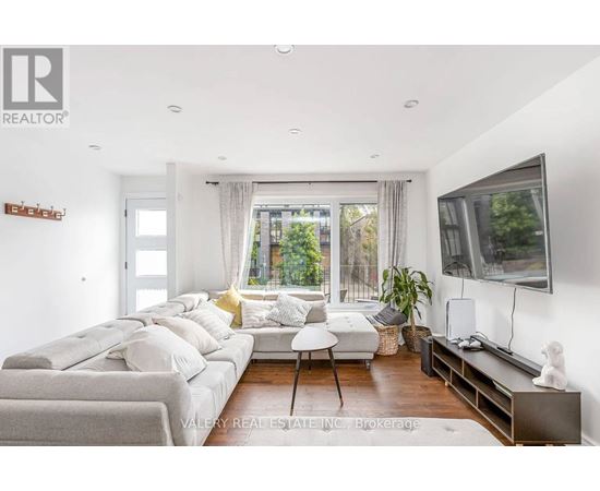 A living room with a grey couch and a television on the wall.