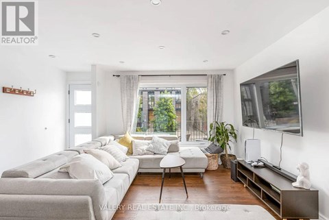 A living room with a grey couch and a television on the wall.