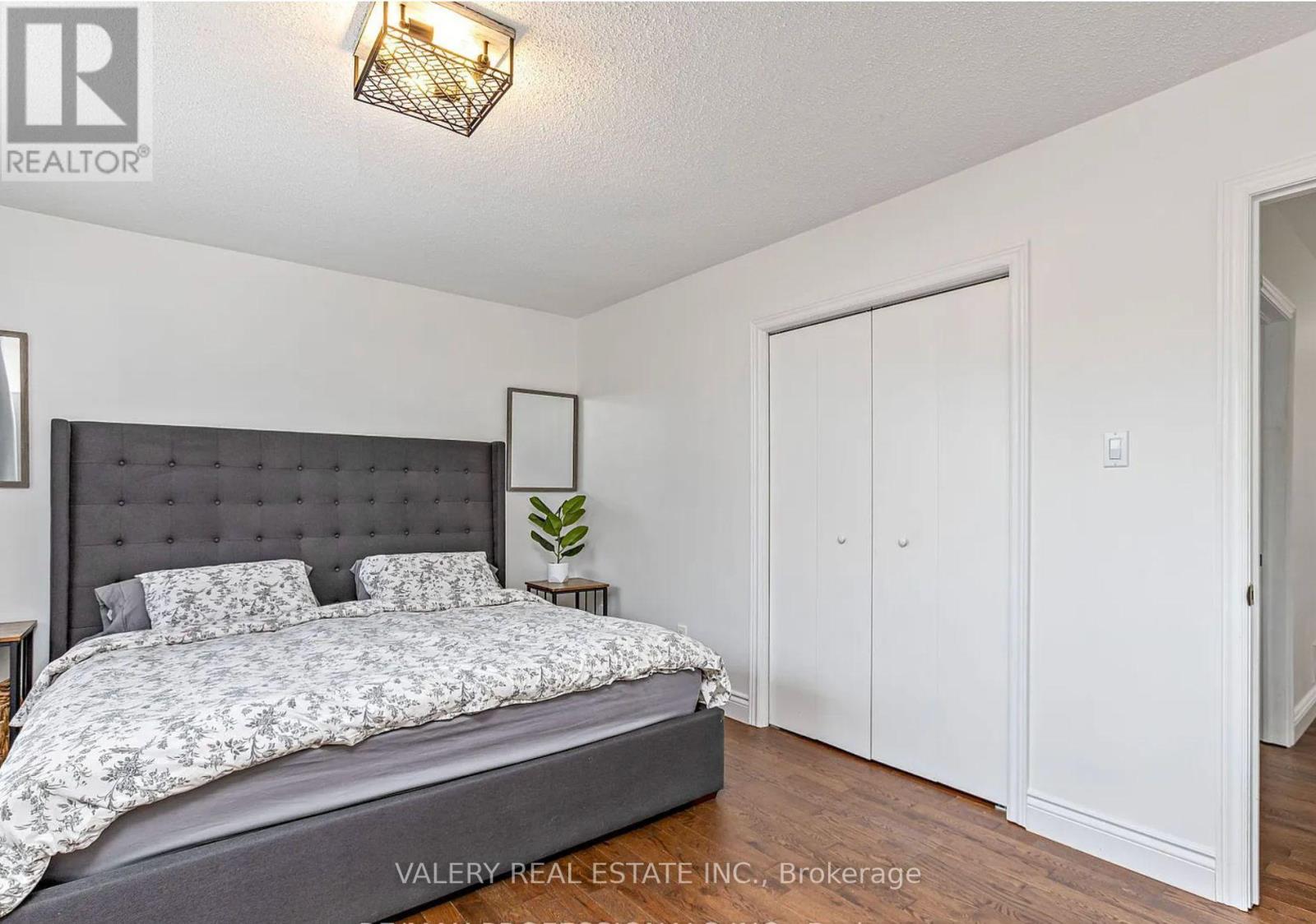 A bedroom with a large bed and a wall-mounted light fixture.