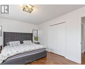 A bedroom with a large bed and a wall-mounted light fixture.