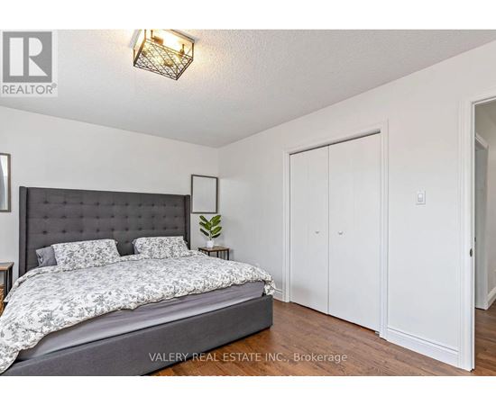 A bedroom with a large bed and a wall-mounted light fixture.