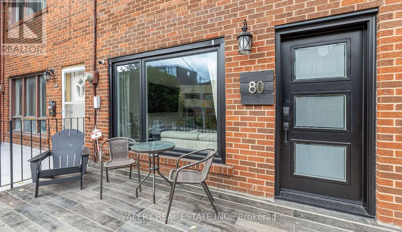 A black door with the number 80 on it is on a brick building.