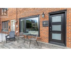A black door with the number 80 on it is on a brick building.
