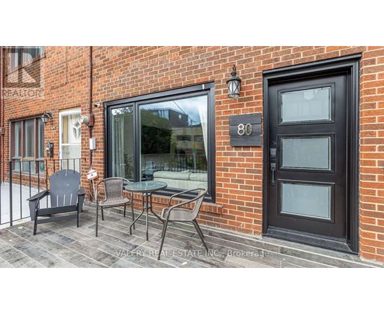 A black door with the number 80 on it is on a brick building.
