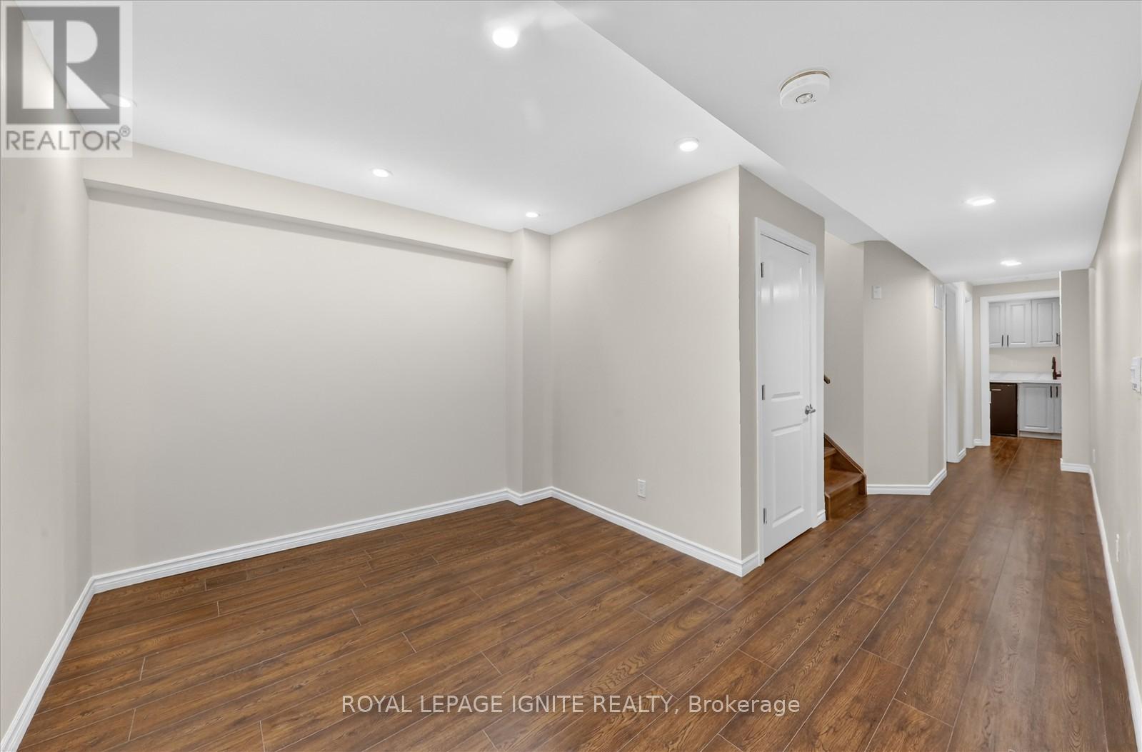 A spacious room with wooden flooring and white walls.