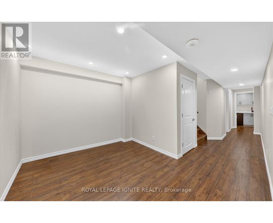 A spacious room with wooden flooring and white walls.