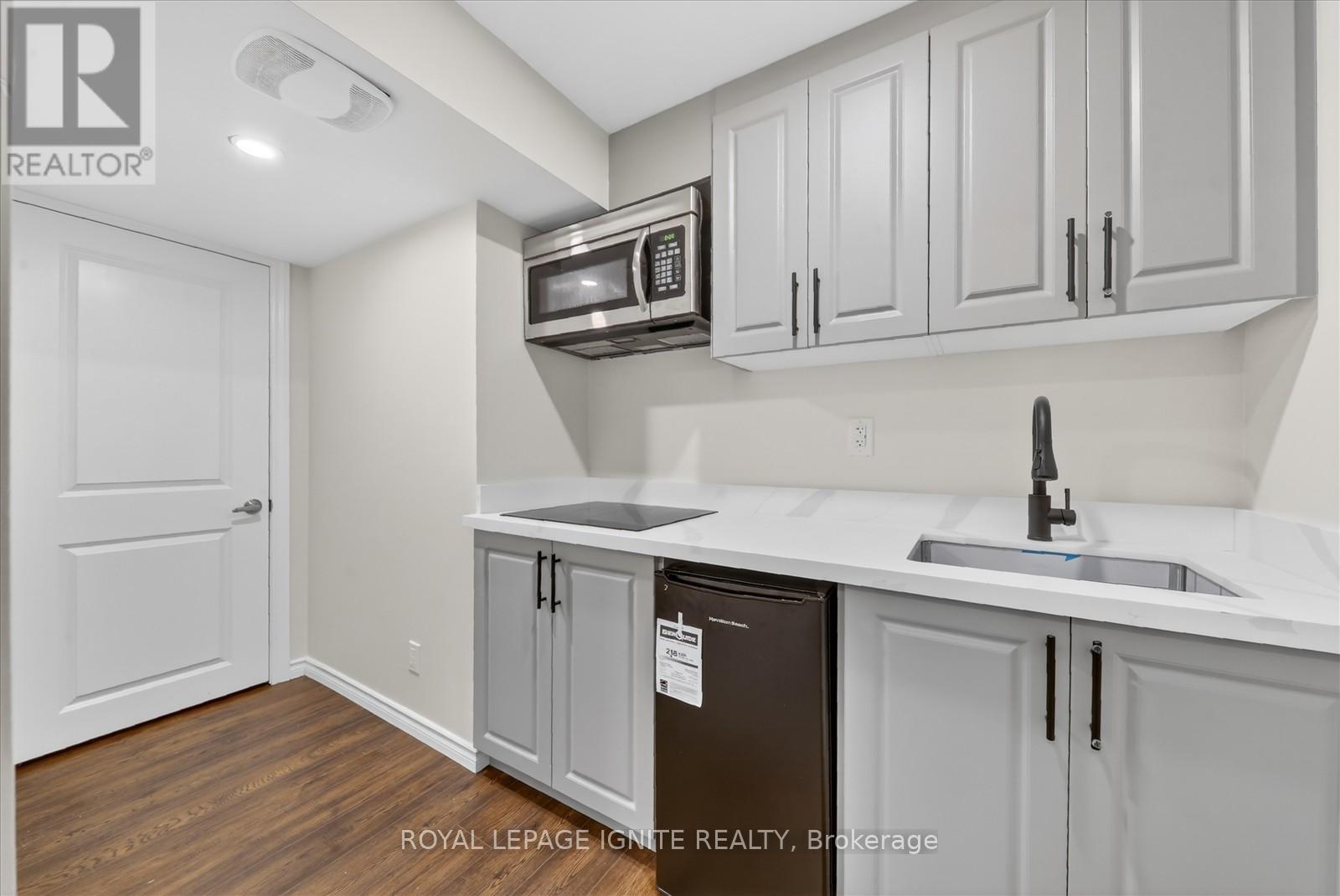 A kitchen with white cabinets and a black fridge.