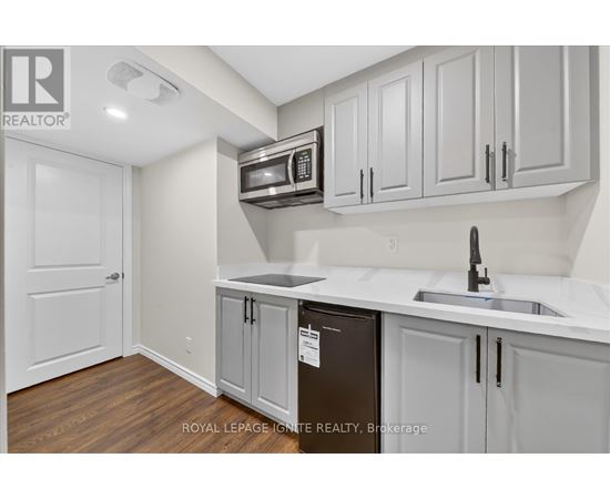 A kitchen with white cabinets and a black fridge.