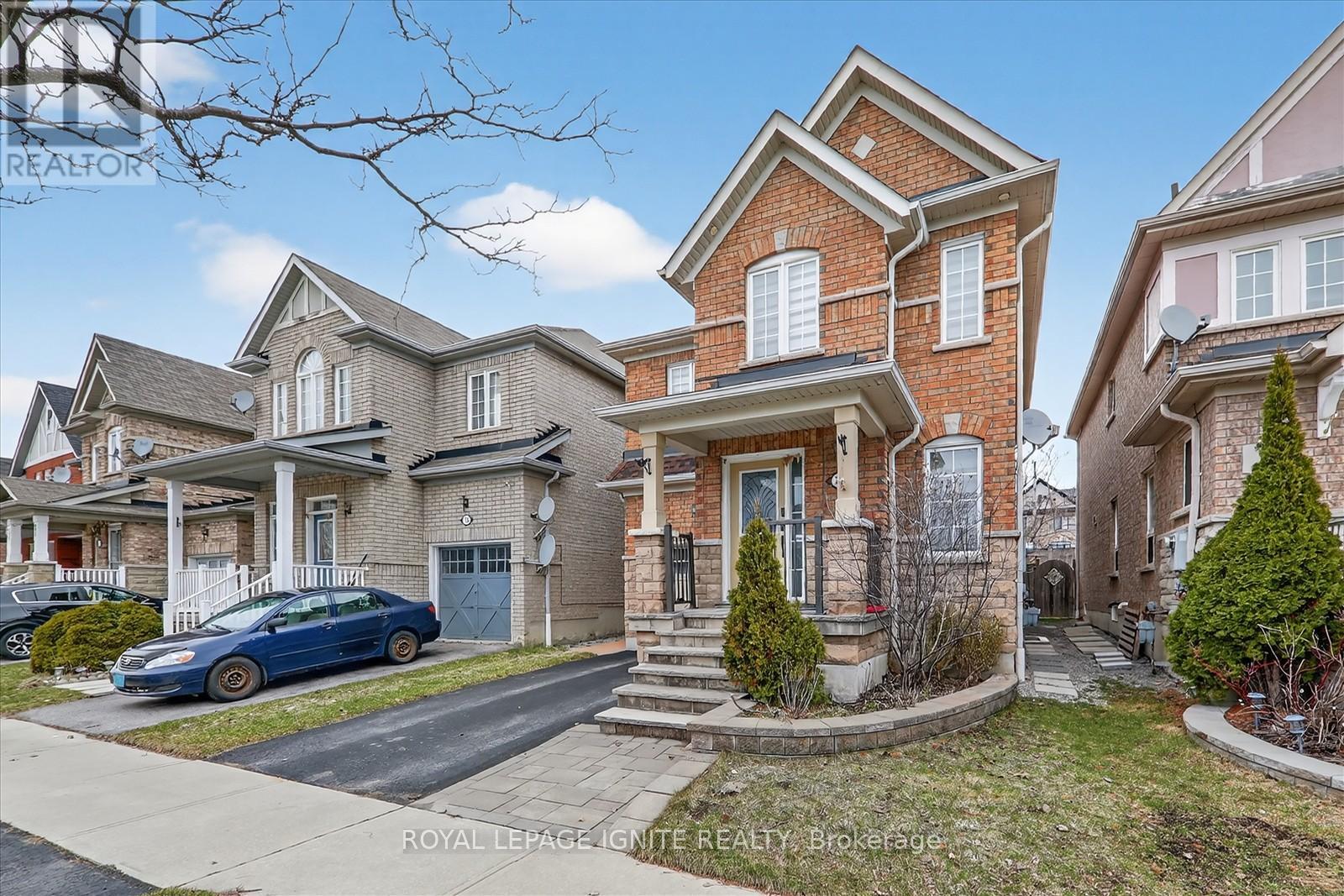 A blue car is parked in front of a house with a sign that says "REALTOR".
