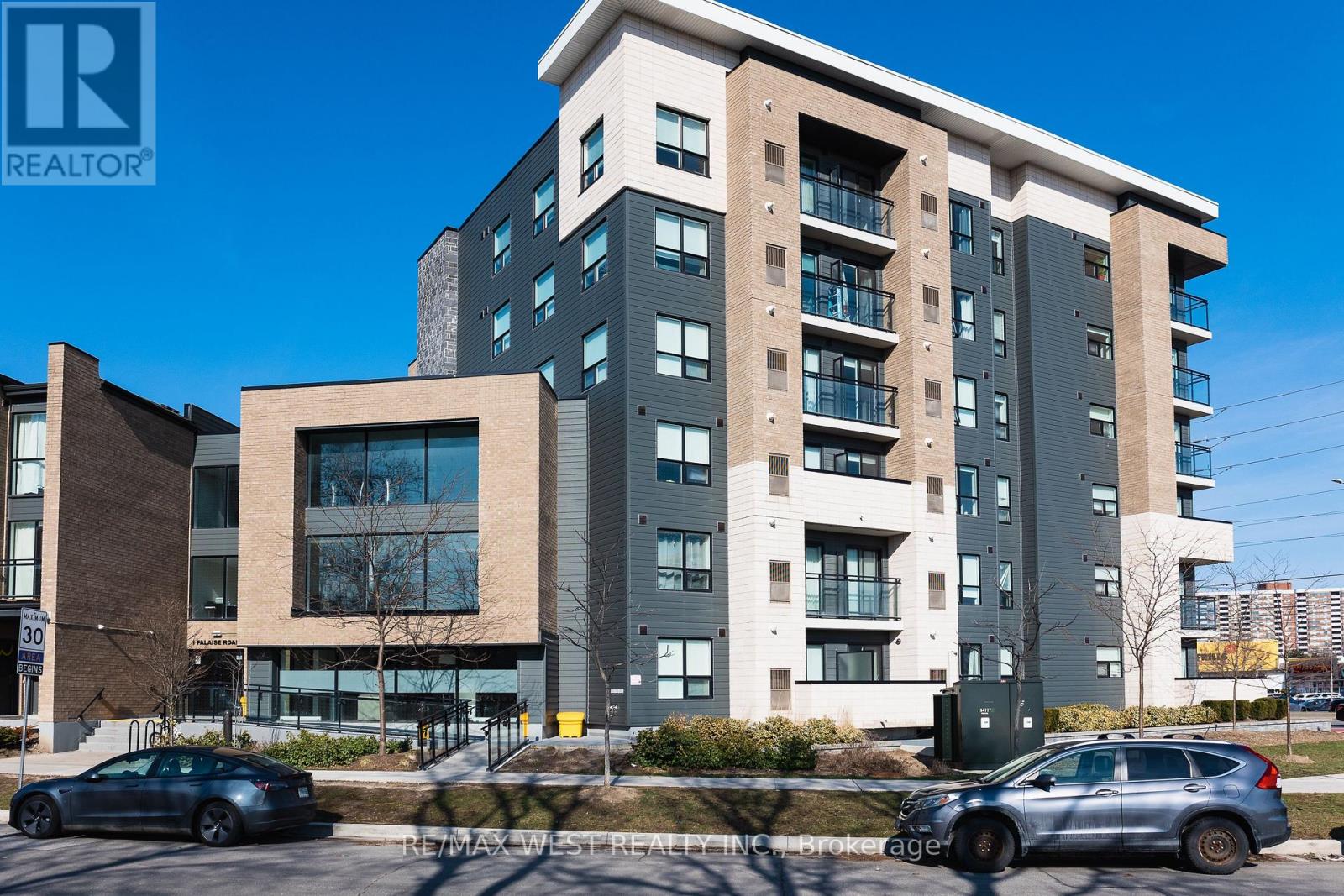 A modern apartment building with cars parked in front.