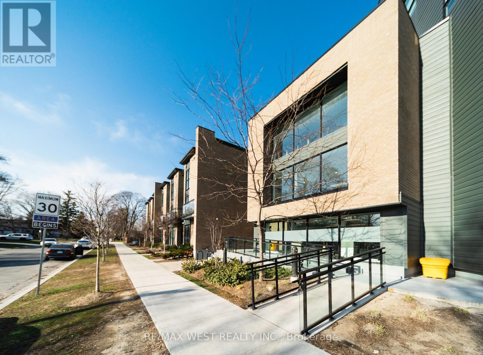 A modern building with a glass entrance and a sign that reads "RE/MAX WEST REALTY INC."