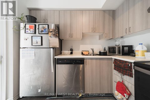 A kitchen with a white fridge, a black dishwasher, and a black stove top.