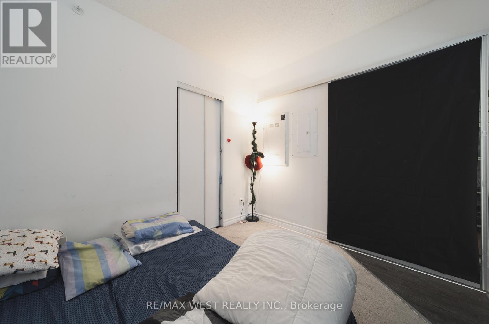 A bedroom with a bed and a lamp on the wall.