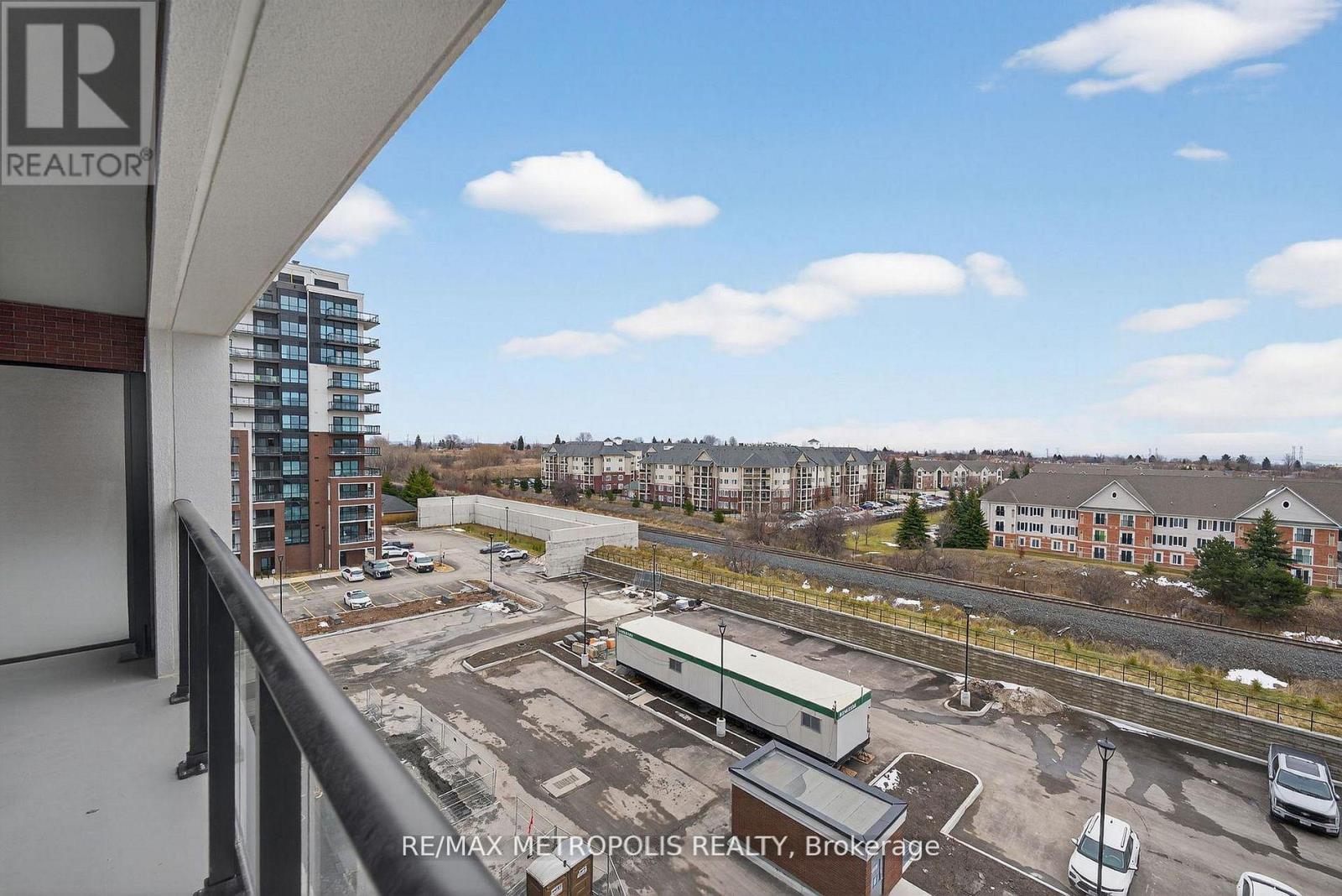 A view from a balcony overlooking a parking lot and buildings.