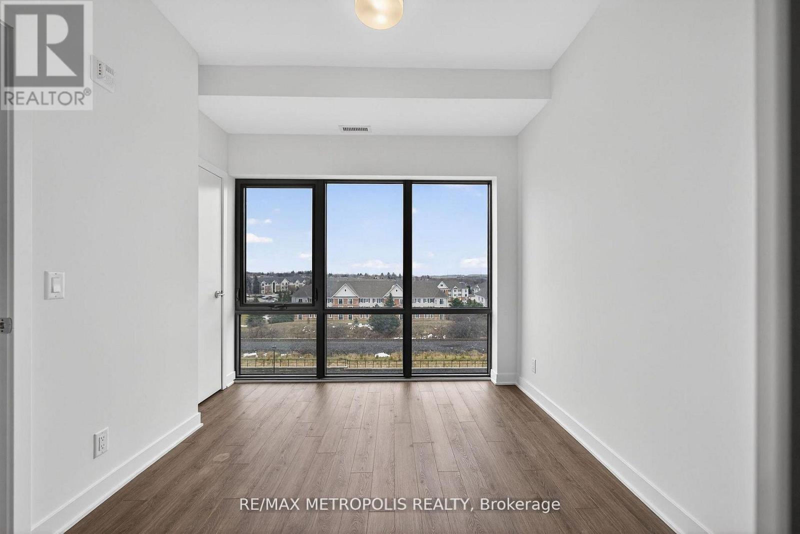A room with a large window and wooden flooring.