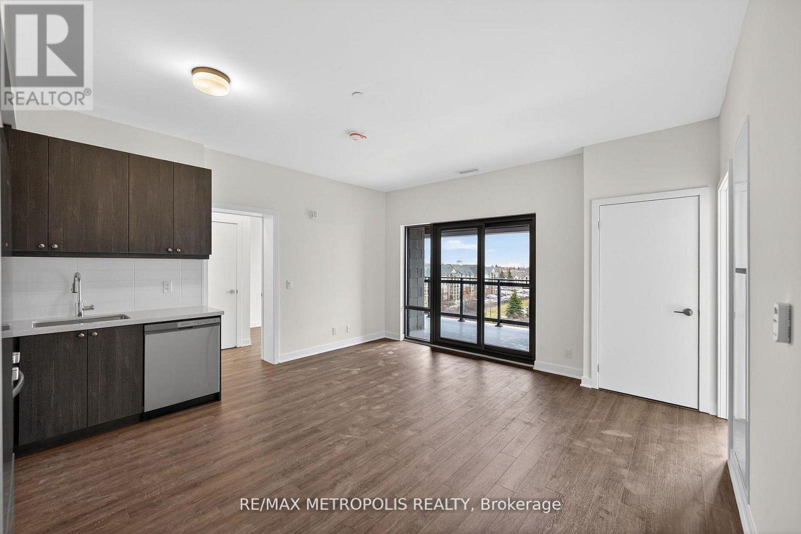 A spacious room with wooden flooring and a large window overlooking a cityscape.
