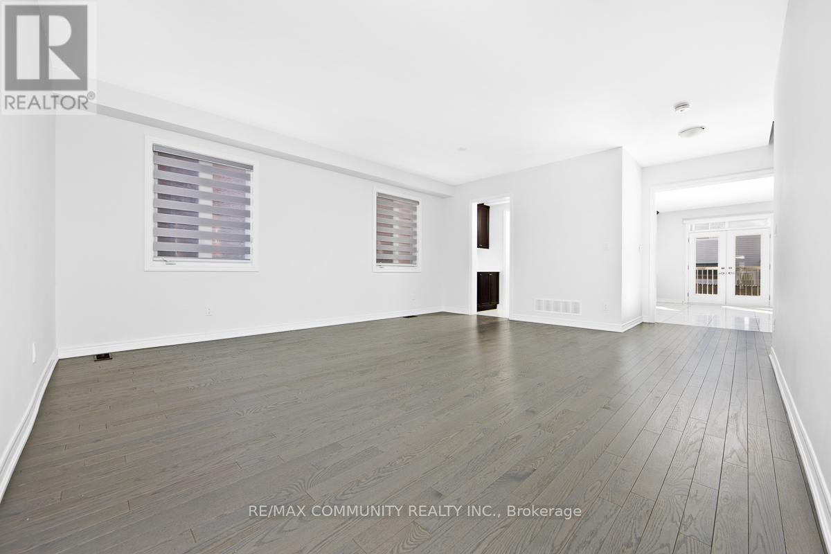 A spacious room with wooden flooring and white walls.