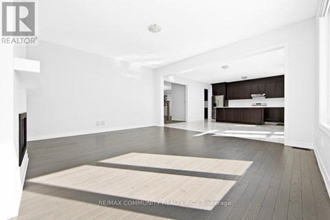 A spacious living room with a television and a rug on the floor.