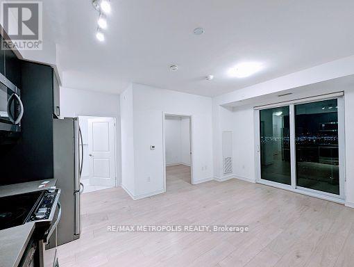 A modern kitchen with white cabinets and a black fridge.
