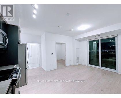 A modern kitchen with white cabinets and a black fridge.