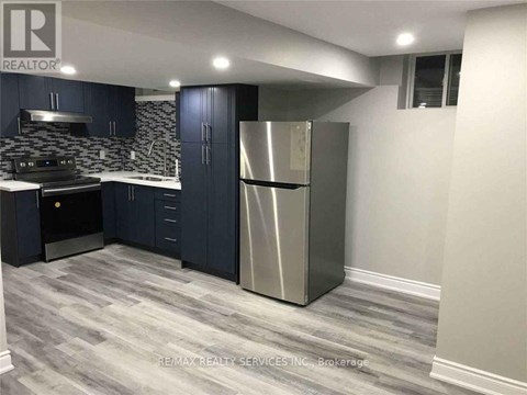 A modern kitchen with dark blue cabinets and a stainless steel refrigerator.