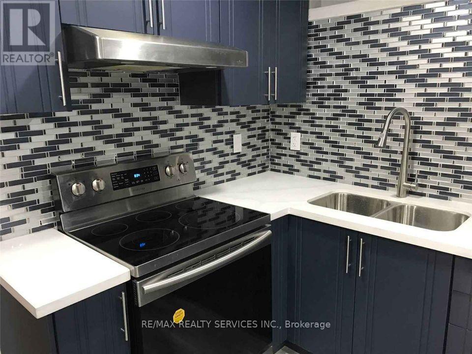 A kitchen with a stove, sink, and a backsplash of tiles.