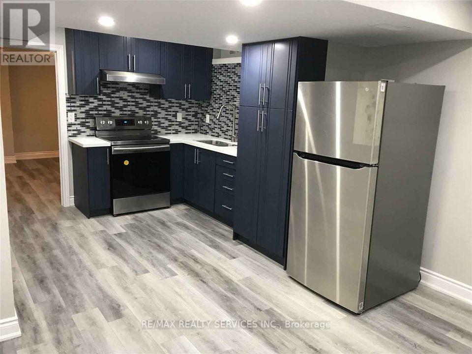 A kitchen with dark blue cabinets and a stainless steel refrigerator.