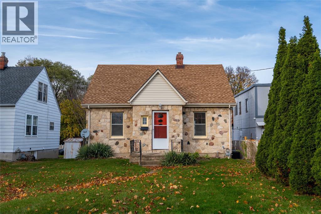 A small house with a red door is surrounded by a grassy area with fallen leaves.