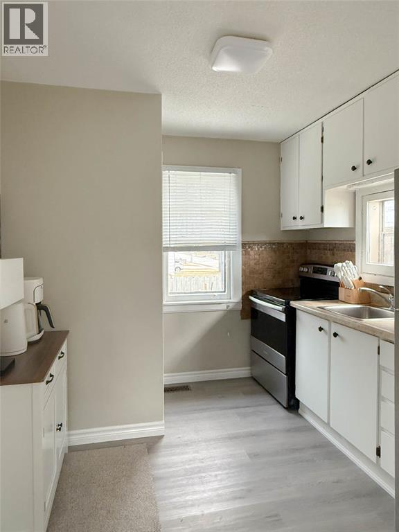 A kitchen with white cabinets and a window.
