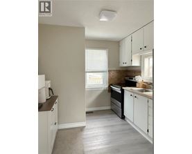 A kitchen with white cabinets and a window.