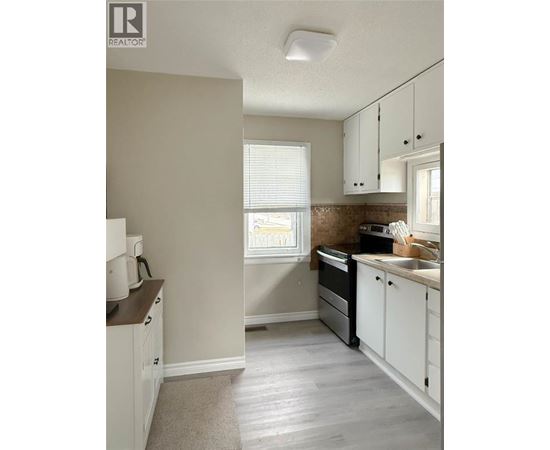 A kitchen with white cabinets and a window.