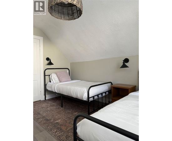 A bedroom with a bed and a wicker lamp.