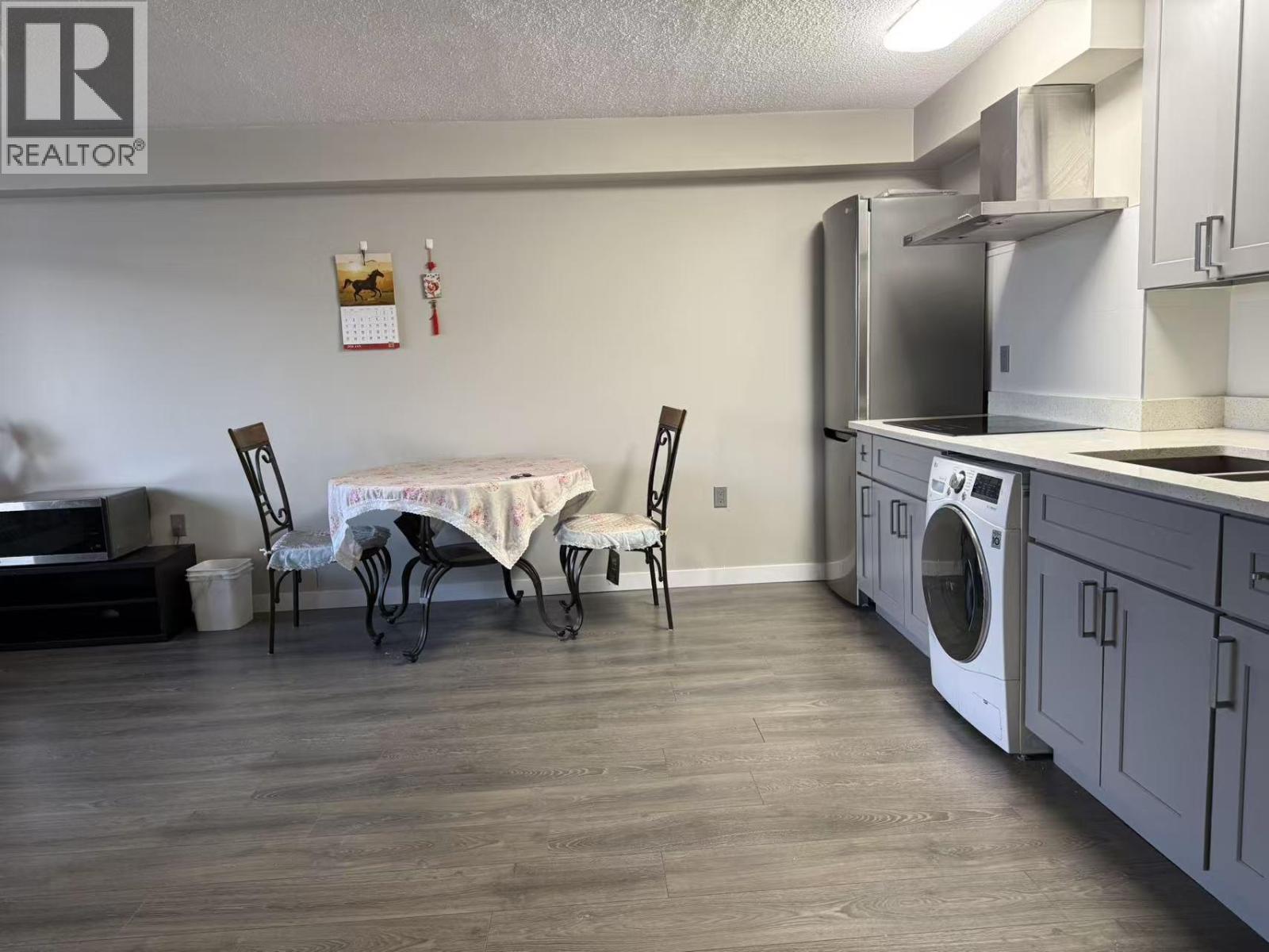 A kitchen with a washing machine and a dining table with chairs.