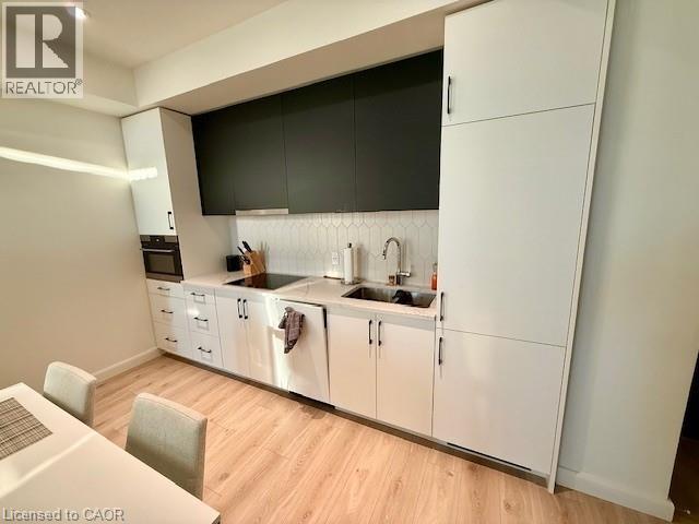 A modern kitchen with white cabinets and a wooden floor.