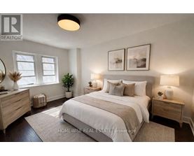 A well-lit bedroom with a large bed, two nightstands, and a plant.