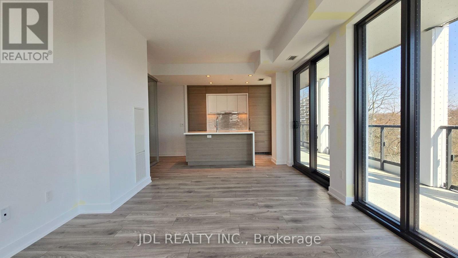 A spacious room with a large window and a wooden floor.