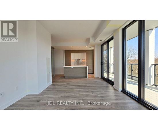 A spacious room with a large window and a wooden floor.