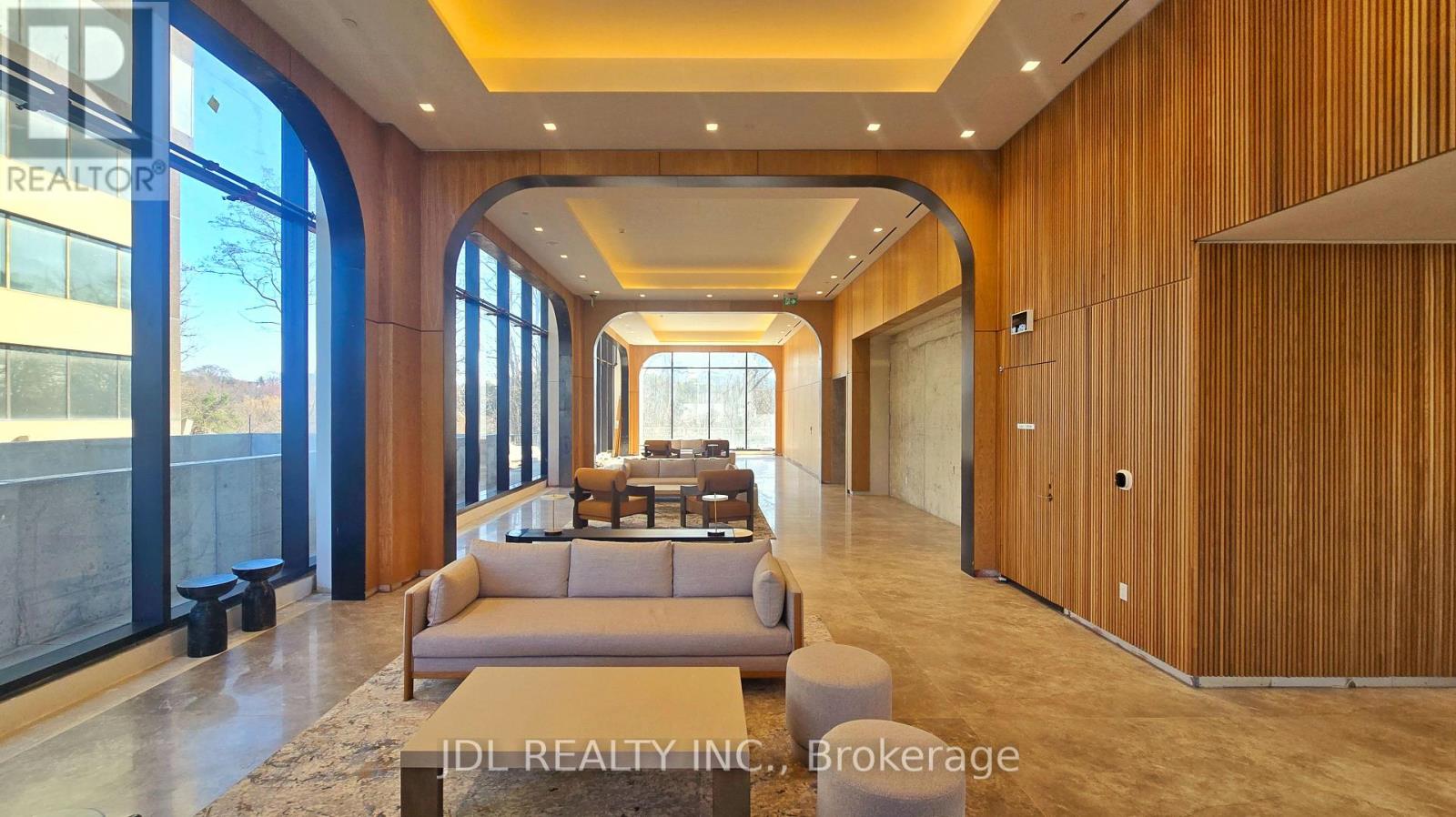 A spacious living room with a large couch and a view of the outdoors through the windows.
