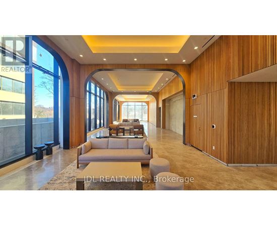 A spacious living room with a large couch and a view of the outdoors through the windows.