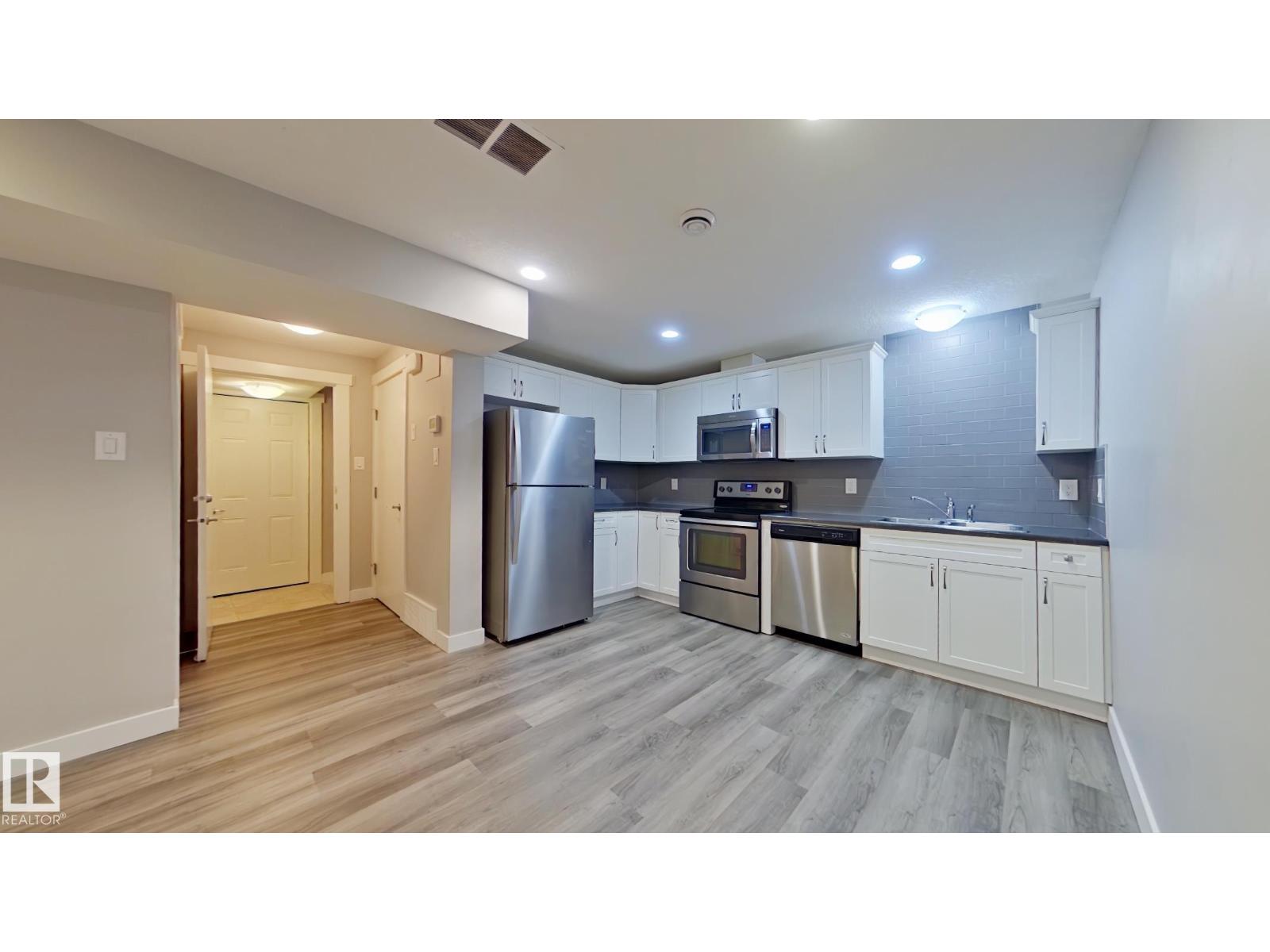 A kitchen with white cabinets and a wooden floor.