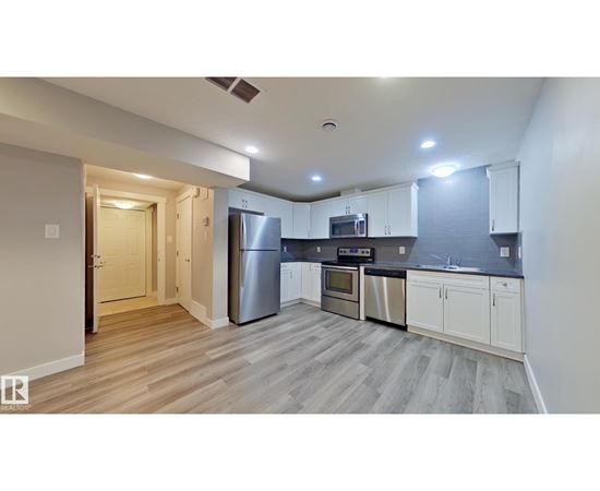A kitchen with white cabinets and a wooden floor.