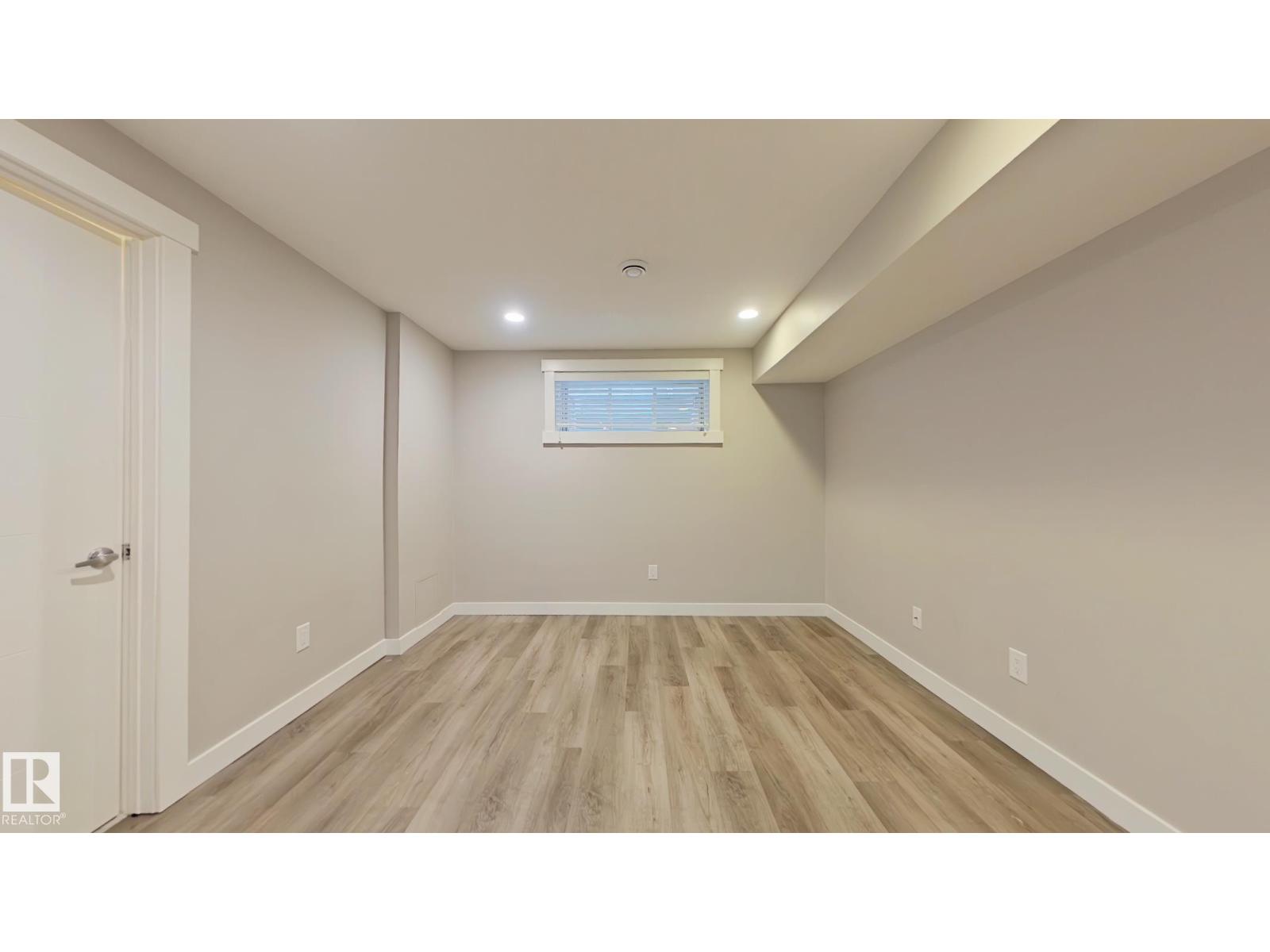 A room with wooden flooring and a window with blinds.