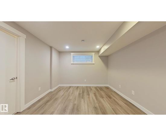 A room with wooden flooring and a window with blinds.